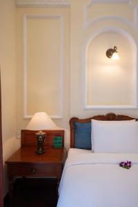 a bedroom with a bed and a table with a lamp at Hotel Majestic Saigon in Ho Chi Minh City