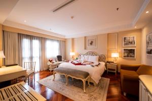 a bedroom with a bed and a living room at Hotel Majestic Saigon in Ho Chi Minh City