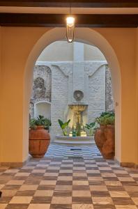 un arco con fontana in un edificio con piante in vaso di Relais - Palazzo Greco Stella a Lamezia Terme