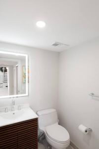 a bathroom with a toilet and a sink and a mirror at Villa at St James Unit A Luxury Pool Villa, Pet Friendly in Miami