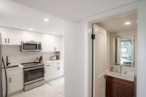 a kitchen with white cabinets and a sink and a microwave at Villa at St James Unit A Luxury Pool Villa, Pet Friendly in Miami