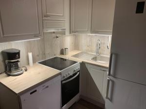 a kitchen with white cabinets and a sink and a refrigerator at Lomahyppäys in Naantali