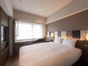 a bedroom with a large white bed and a window at insomnia KYOTO OIKE in Kyoto