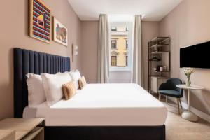 a bedroom with a large white bed and a tv at Numa I Linea in Rome