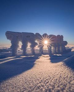 un sole che splende su una struttura in pietra nella neve di Solbjørnlia Apartments a Trysil