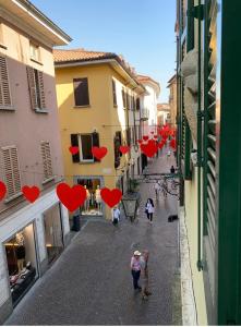 Un gruppo di persone che camminano per strada con cuori appesi agli edifici di cavaedium guest house ad Arona