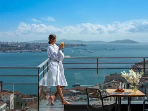 a woman standing on a balcony holding a drink at Sofitel Istanbul Taksim in Istanbul