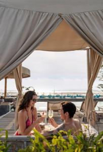 twee mensen aan een tafel met een glas wijn bij Kardia Resort Gili Trawangan A Pramana Experience in Gili Trawangan