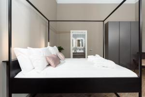 een groot wit bed met een zwart frame en kussens bij Q71 TIMELESS SUITES in Turijn