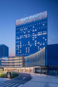 een groot blauw gebouw met een weg ervoor bij Hyatt Regency Guangzhou Zengcheng in Guangzhou