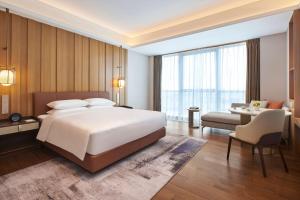 een slaapkamer met een groot wit bed en een bureau bij Hyatt Regency Guangzhou Zengcheng in Guangzhou