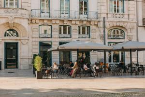 personas sentadas en mesas fuera de un edificio con sombrillas en 1908 Lisboa Hotel, en Lisboa