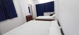 um pequeno quarto com duas camas e cortinas azuis em Mahadev Home Stay em Varanasi