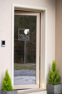 a glass door with a sign on it with two plants at Villa dei Larici in Camigliatello Silano