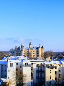 duży budynek z śniegiem na dachach budynków w obiekcie Schlosskönig - Modernes & zentrales Apartment mit Balkon und Arbeitsplatz w mieście Schwerin