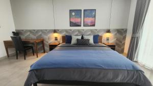 um quarto com uma cama azul, uma secretária e uma mesa em KhaoTao Homestay เขาเต่าโฮมสเตย์ em Khao Tao