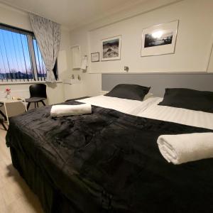 B&B Guesthouse - Bed and Breakfast Keflavik Centre في كيفلافيك: غرفة نوم بسرير كبير وملاءات بيضاء وسوداء