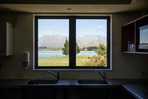 a kitchen window with a view of a lake and mountains at Haka House Lake Tekapo in Lake Tekapo