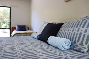 a bed with blue and white sheets and pillows at Kanuka Ridge Lodge in Marahau