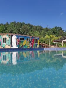 une piscine d'eau avec un bâtiment orné de graffitis dans l'établissement VRISA Mountain Retreat, à Pune