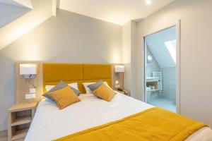 a bedroom with a large white bed with yellow pillows at Hotel Saint Augustin in Strasbourg