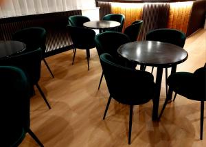 a row of tables in a room with green chairs at Hotel Meranda in Camigliatello Silano