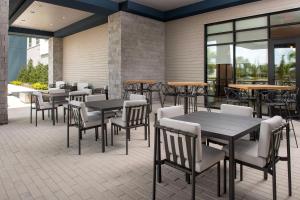 a patio with tables and chairs and tables and windows at Home2 Suites Orlando Southeast Nona in Orlando