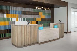 a lobby with wooden reception desks and a colorful wall at Home2 Suites Orlando Southeast Nona in Orlando