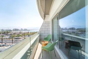 uma varanda com cadeiras verdes e vista para o oceano em Luxury Apartments - By Harim em Eilat