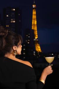 a woman holding a wine glass in front of the eiffel tower at Quinzerie hôtel in Paris