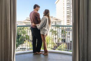 a man and woman standing on a balcony looking out a window at Sheraton Princess Kaiulani in Honolulu