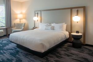 a hotel room with a large bed and a chair at Fairfield Inn & Suites by Marriott Nashville Airport in Nashville