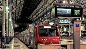 un train rouge s'introduit dans une gare dans l'établissement April Square by Lisbon with Sintra, à Amadora