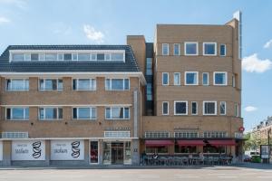 ein großes Backsteingebäude auf einer Straße mit einem Geschäft in der Unterkunft Kaboom Hotel Maastricht in Maastricht