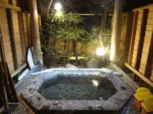 a hot tub in a garden at night at IZUNA INN & SPA - the veggie delights in Ito