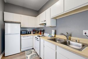 a kitchen with white cabinets and a sink at Okaloosa Island Studio in Fort Walton Beach