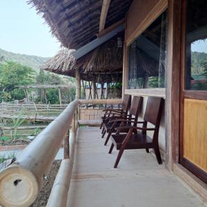 a row of chairs sitting on the porch of a building at Homestay field - bungalow, Ha giang loop tour, motorbikes rental in Ha Giang