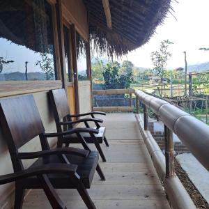 a row of chairs sitting on the porch of a building at Homestay field - bungalow, Ha giang loop tour, motorbikes rental in Ha Giang