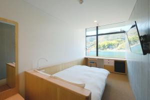 een slaapkamer met een bed en een groot raam bij BONAPOOL in Onomichi