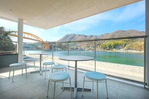 een balkon met tafels en stoelen en uitzicht op het water bij BONAPOOL in Onomichi