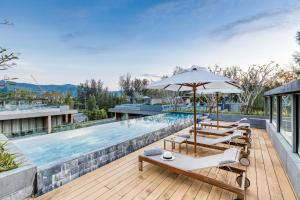 an outdoor pool with lounge chairs and an umbrella at Twinpalms MontAzure Phuket Resort in Kamala Beach