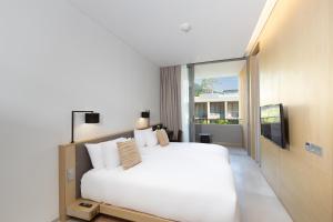 a bedroom with a white bed and a large window at Twinpalms MontAzure Phuket Resort in Kamala Beach