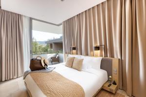 a bedroom with a white bed and a window with curtains at Twinpalms MontAzure Phuket Resort in Kamala Beach