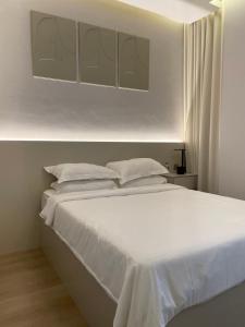 - un lit blanc avec des draps et des oreillers blancs dans l'établissement 1 BR Luxury Apt by AJ Aljada, à Charjah