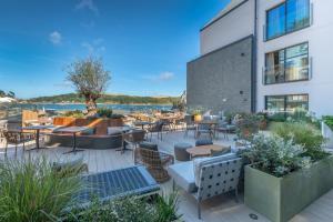 un patio con mesas y sillas y un edificio en Harbour Beach Club, Hotel & Spa en Salcombe