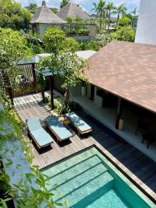 een terras met ligstoelen en een zwembad bij Luna Ola Villa Berawa in Canggu