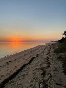 einen Strand mit Sonnenuntergang über dem Wasser in der Unterkunft Troia Apartments in Troia