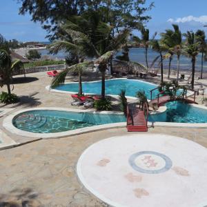 uma piscina de resort com palmeiras e o oceano em Lily Palm Resort em Watamu