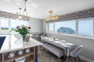 jadalnia ze stołem, krzesłami i oknami w obiekcie Goferydd, South Stack, Anglesey, 4 bed luxury home, hot tub, dog friendly w mieście Holyhead