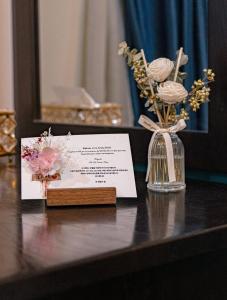 a table with a card and a vase of flowers at La Serena Boutique Hotel in Ho Chi Minh City